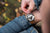 Reloj de hombre en la muñeca con correa de cuero marrón y caja plateada, bisel negro