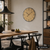AMS-Wanduhr mit Messing-Zifferblatt, schwarzen Zeigern und rundem Rahmen an der Wand