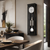 "Reloj de pared en marco negro con frente de cristal, esfera redonda y barras de sonido de acero inoxidable"