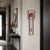 Reloj de pared con marco rojo y caja interior rectangular, pesa roja visible