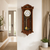 Reloj de pared de madera oscura con esfera y péndulo dorado en cristal.