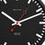 Esfera de reloj de pared en detalle: fondo negro, manecillas rojas, índices de línea blancos.