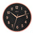Reloj de pared redondo con esfera negra, bisel en oro rosa y números romanos