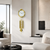 Reloj de pared dorado con péndulos decorativos sobre pared blanca