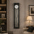 "Reloj de pared con marco negro, esfera redonda y péndulo de metal en cristal"