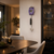 "Reloj de pared con esfera violeta, péndulo largo y remate negro"