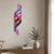 Reloj de pared con patrón de ondas de colores, péndulo violeta y números blancos