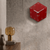 Reloj de pared redondo rojo de acrílico en la pared con manecillas blancas y logo de Hermle