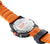 Pulsera de hombre con correa naranja, fondo de caja visible "NEVER GIVE UP"