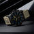 Reloj de hombre con correa beige y esfera negra, marcadores luminosos en azul