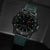 Reloj de hombre en vista lateral con caja negra y correa de silicona verde; números luminosos.