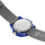 Parte inferior de la caja de un reloj de pulsera para hombre: fondo plateado, componente azul, correa textil gris.
