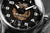 Primer plano de reloj de pulsera para hombre: esfera negra con números grandes, manecillas plateadas