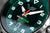 Reloj de hombre con esfera verde, manecillas luminosas y acento naranja