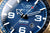 Esfera de reloj de hombre en primer plano con superficie azul, números y manecillas grandes