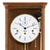 Primer plano de reloj de pared de madera: esfera blanca con números romanos y borde dorado